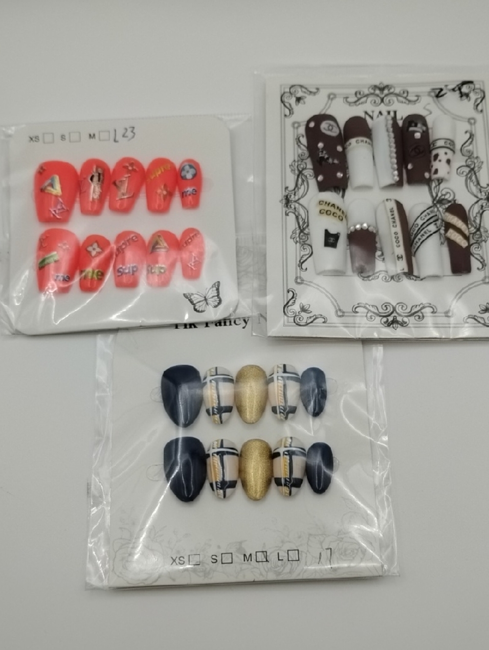3 Sets Of Handmade Nails With Luxury Brand Logos On Them